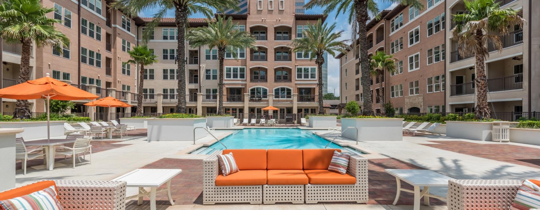 a pool in a courtyard with palm trees and buildings in the background