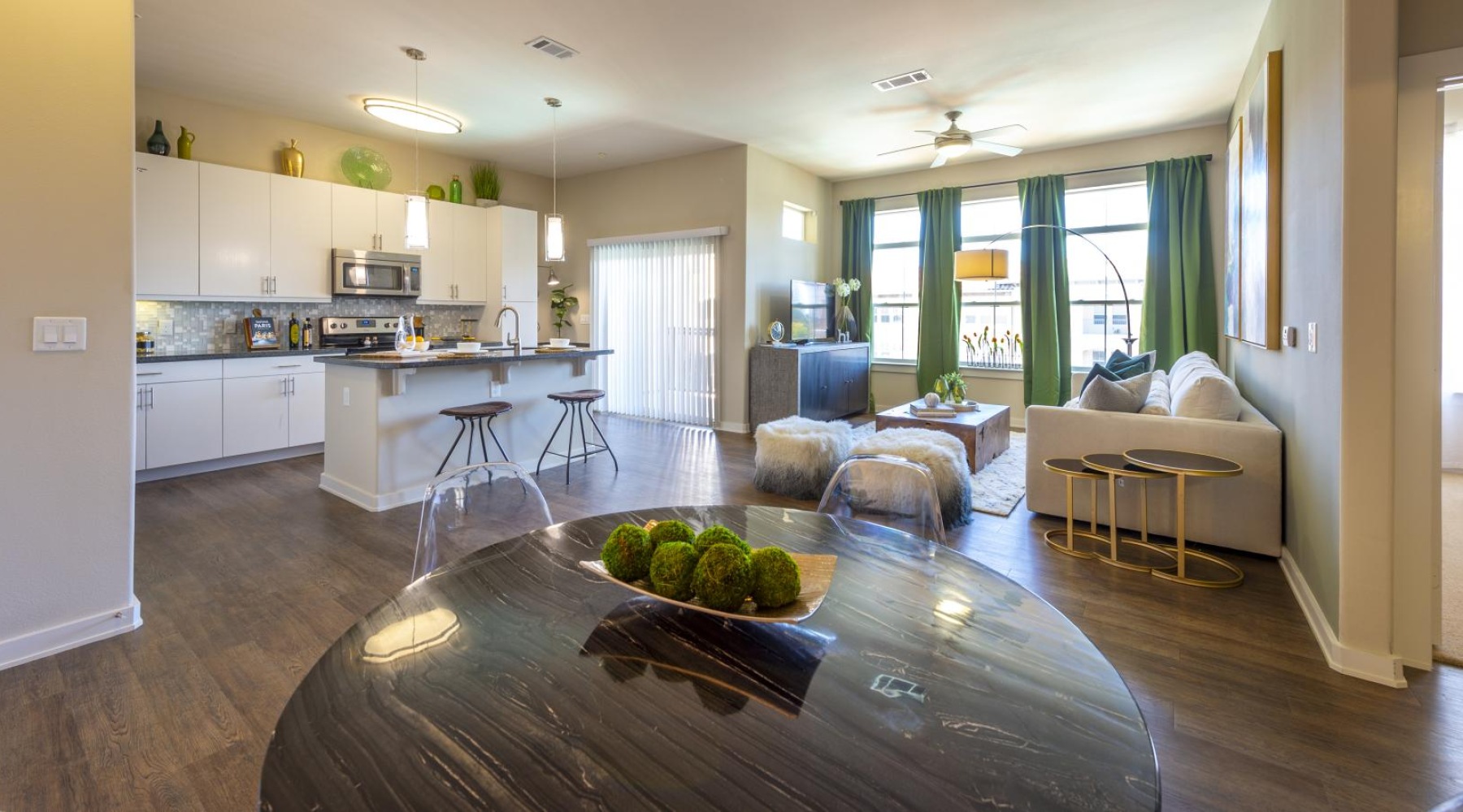 a living and dining area connected to a kitchen with many windows