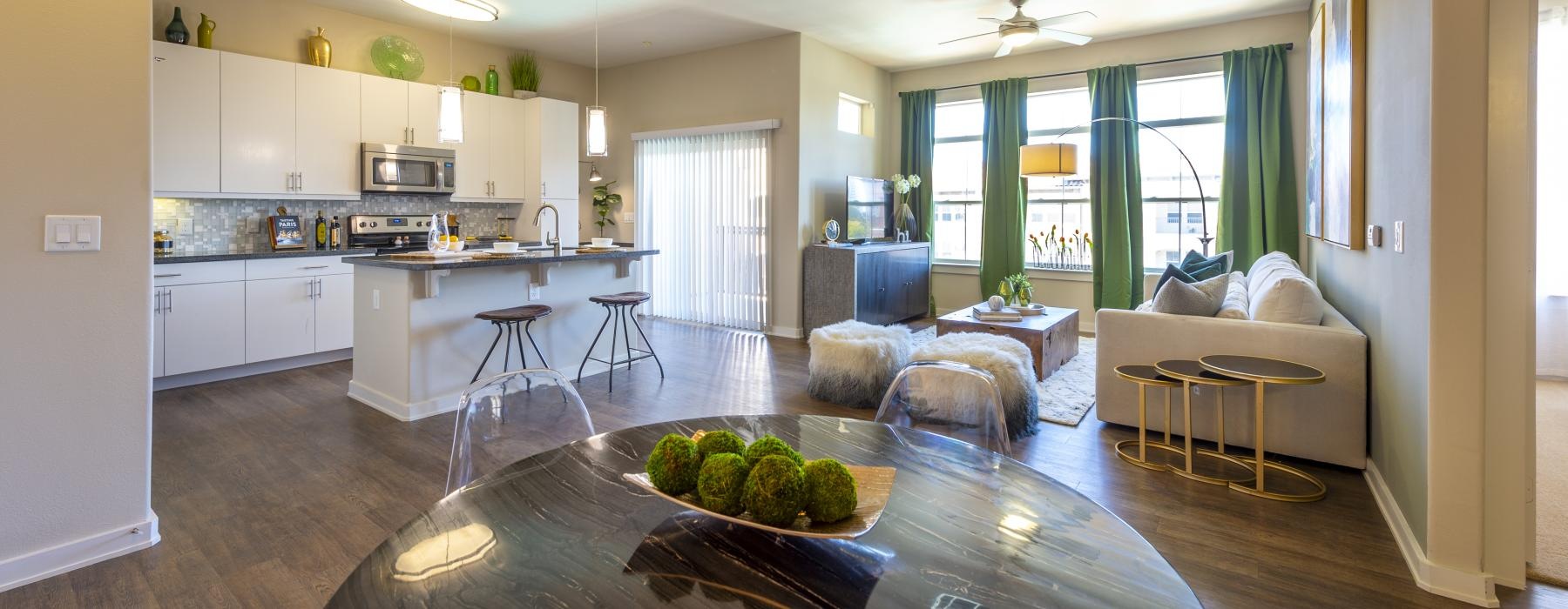 a living and dining area connected to a kitchen with many windows